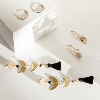 Lifestyle image of statement brass tassel hoops and recycled gold drops and hoops.
