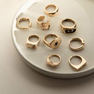 Recycled gold statement signet rings on a ceramic plate.