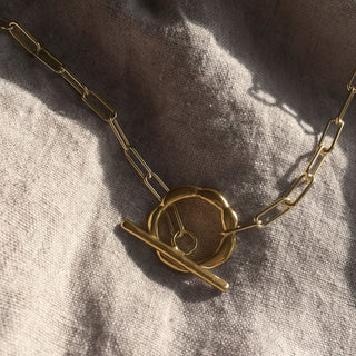Gold plated Puddle choker necklace handcrafted by Claire Hibon from recycled material on a linen background.