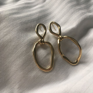Gold plated Puddle drop earrings handmade sustainably by Claire Hibon from recycled and reused material on a soft background.