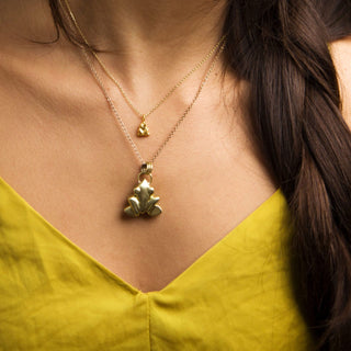 Model wearing tiny frog pendant in 24ct gold vermeil plating and a large frog pendant made from recycled brass