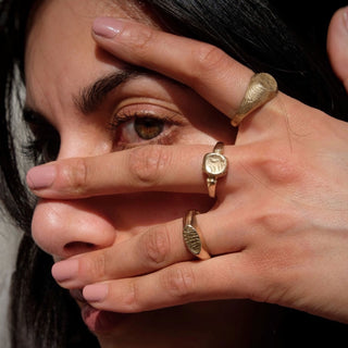 Model wearing collection of rings including the Melt brass signet ring by Lunaflux.